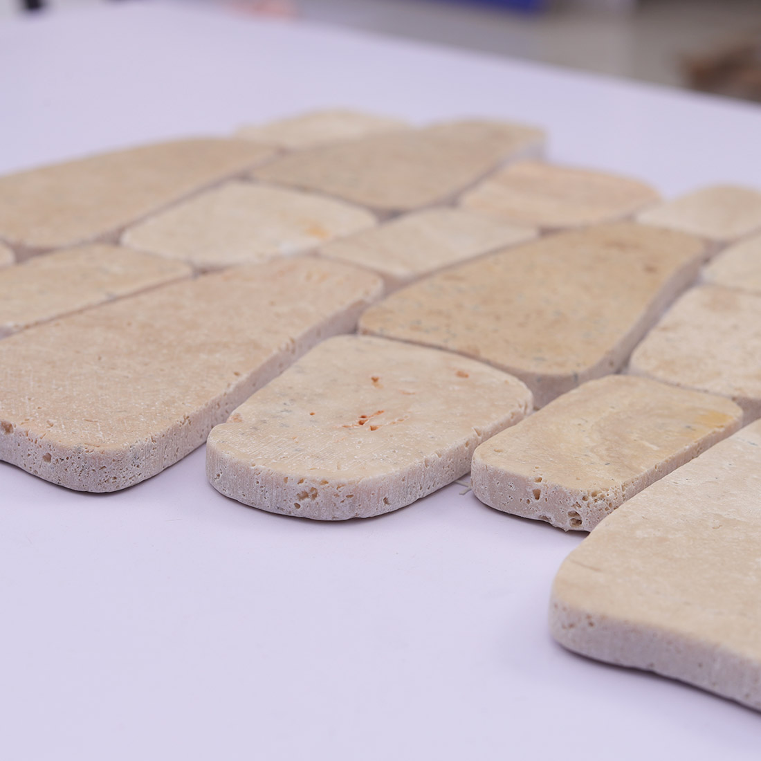 Angled view of beige pebble stone mosaic showing thickness and porous edges