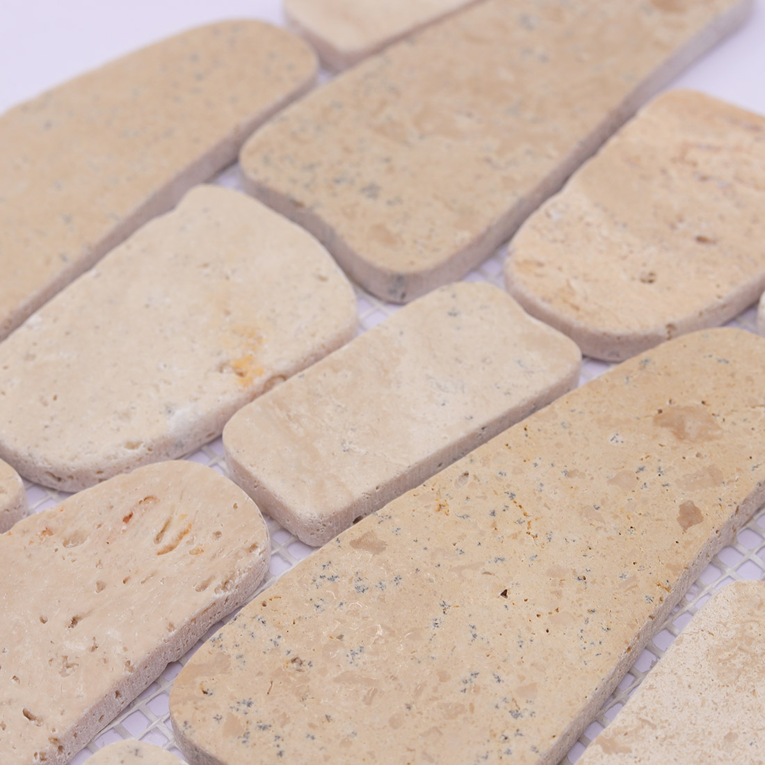 Mixed-shape beige stone mosaic tiles with rounded edges and natural texture