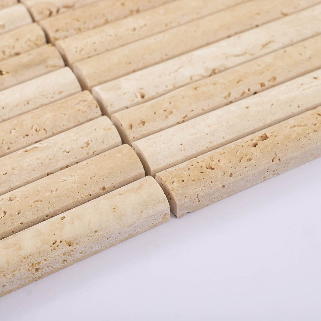 Edge view of beige travertine strip mosaic showing thickness and natural pores