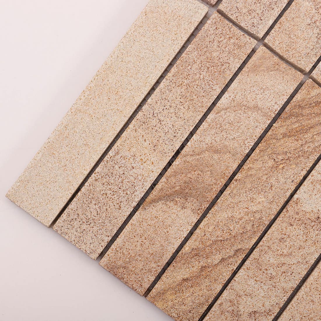 Angled closeup of beige stone linear mosaic sheet corner and tile texture
