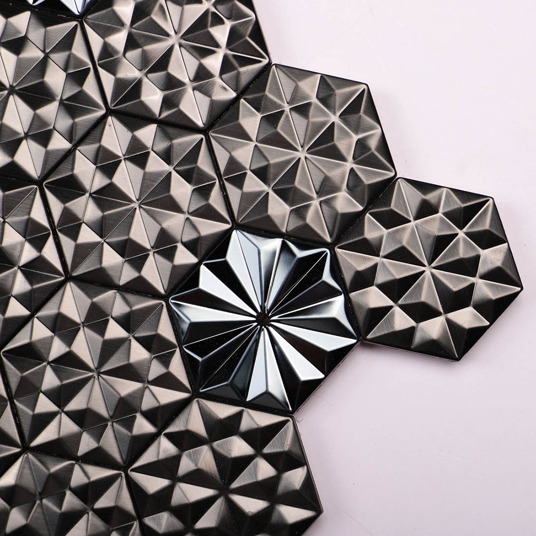Close-up of black geometric metal mosaic tiles with faceted star patterns
