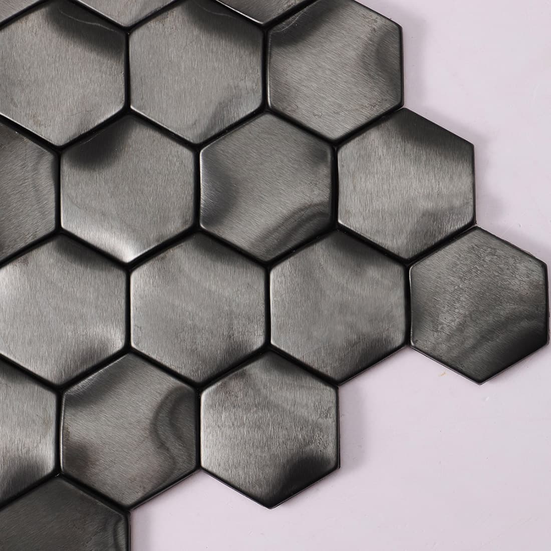 Side angled view of black hexagon metal mosaic tiles showing the tile edges.