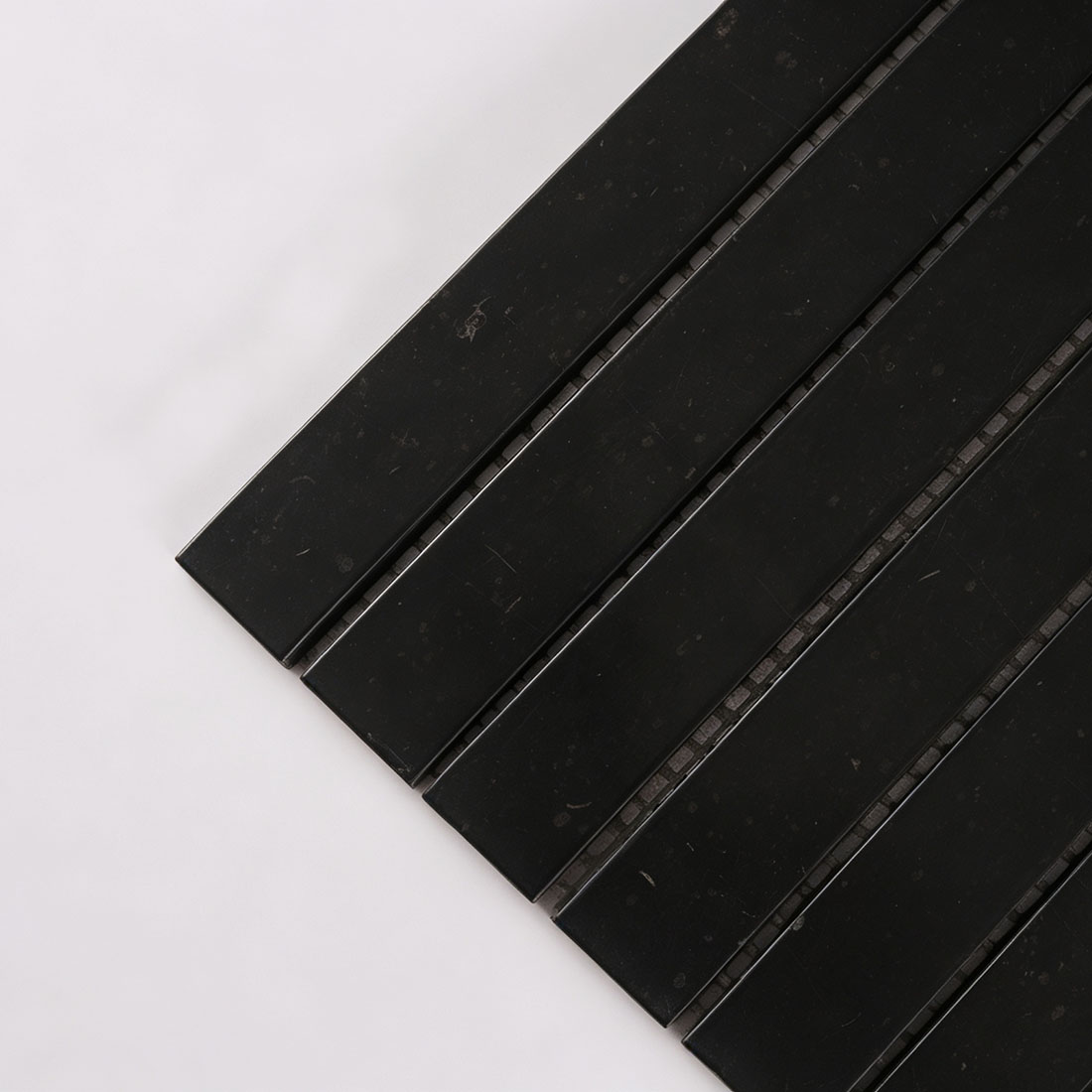 Close-up of narrow black marble bar mosaic tile strips