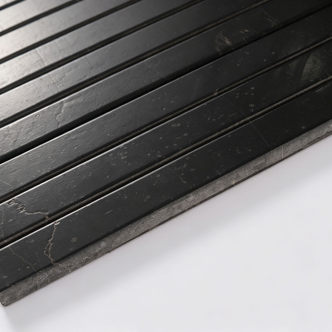 Close-up showing the edge thickness of black marble bar mosaic tile