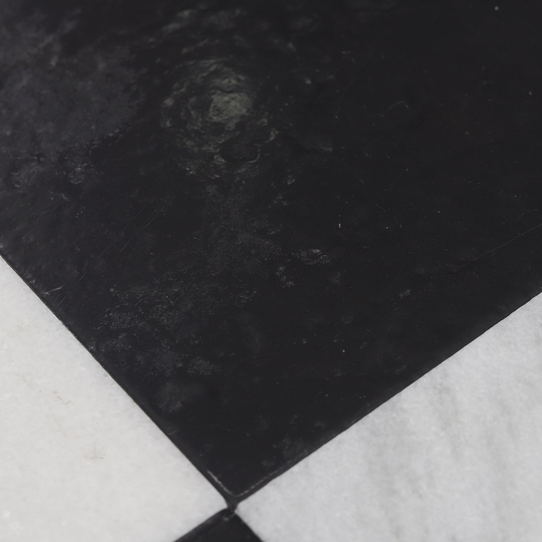 Close-up of natural black marble surface framed by white marble border tile