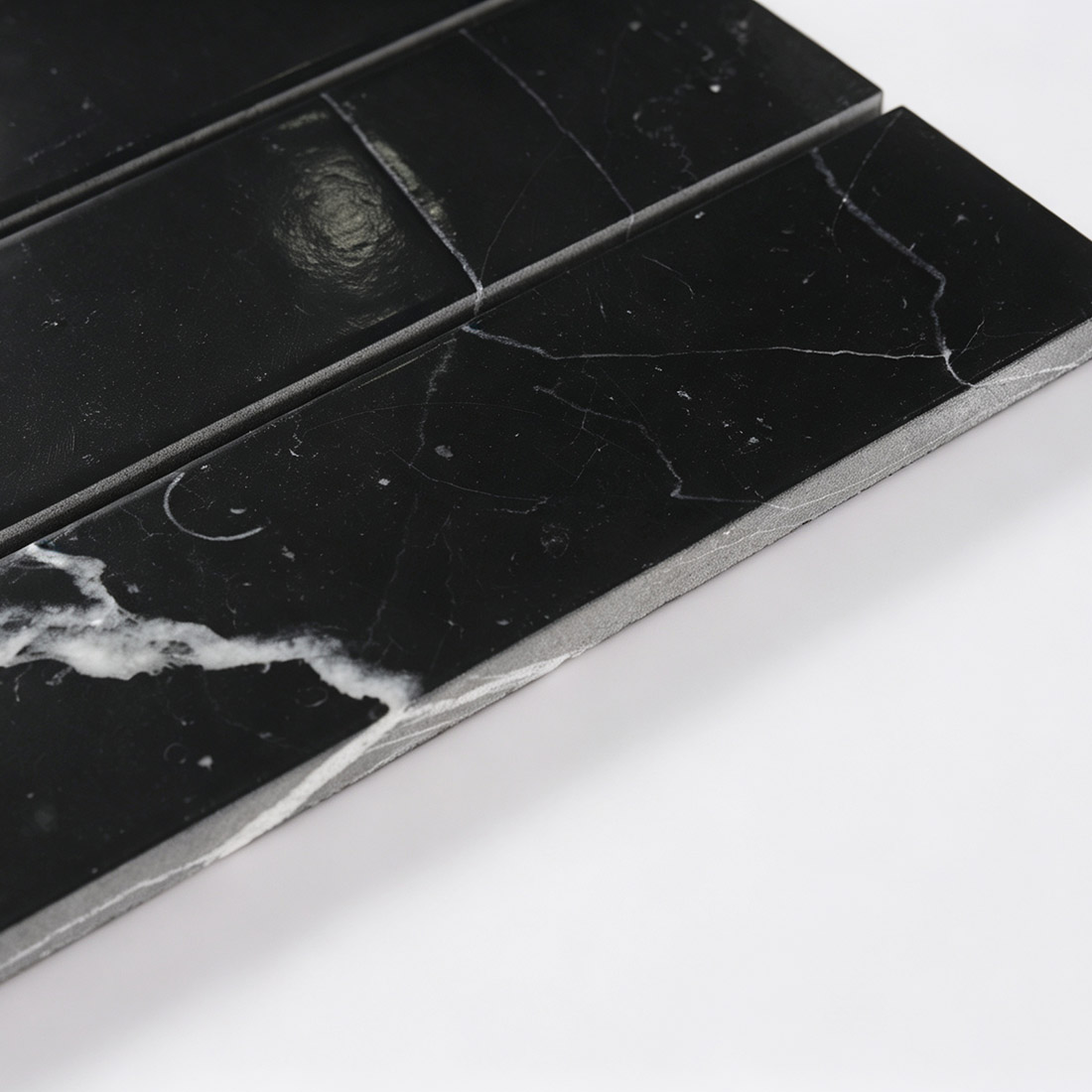 Close-up showing black marble wide bar mosaic tile thickness and edges