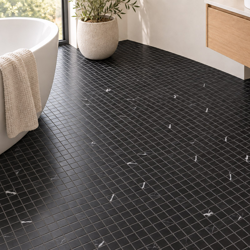 Black mosaic bathroom floor beside a white bathtub and floating wood vanity