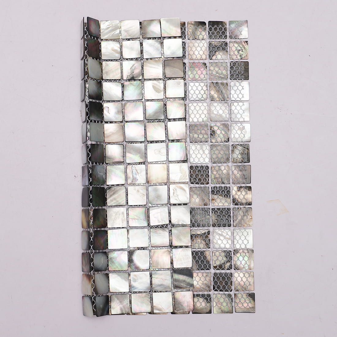 Half front half back view showing black mother of pearl tiles and mesh backing
