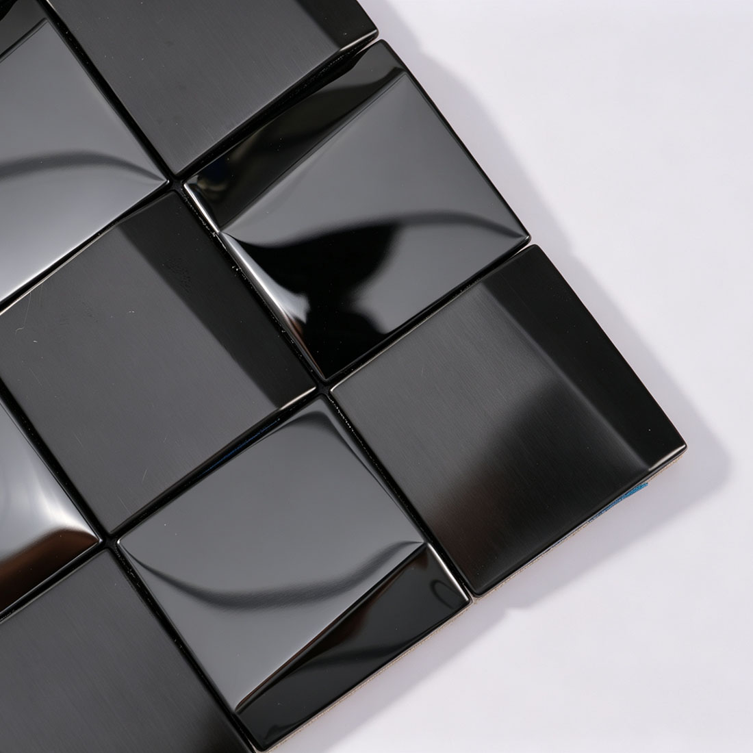 Corner detail of black square metal mosaic tiles with brushed texture