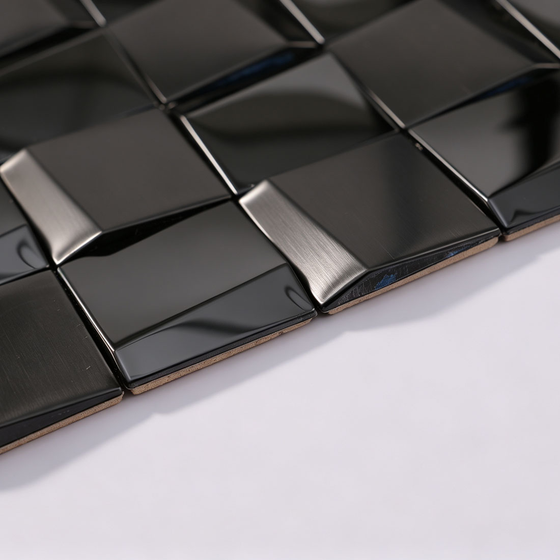 Angled view of black square metal mosaic tile sheet edge
