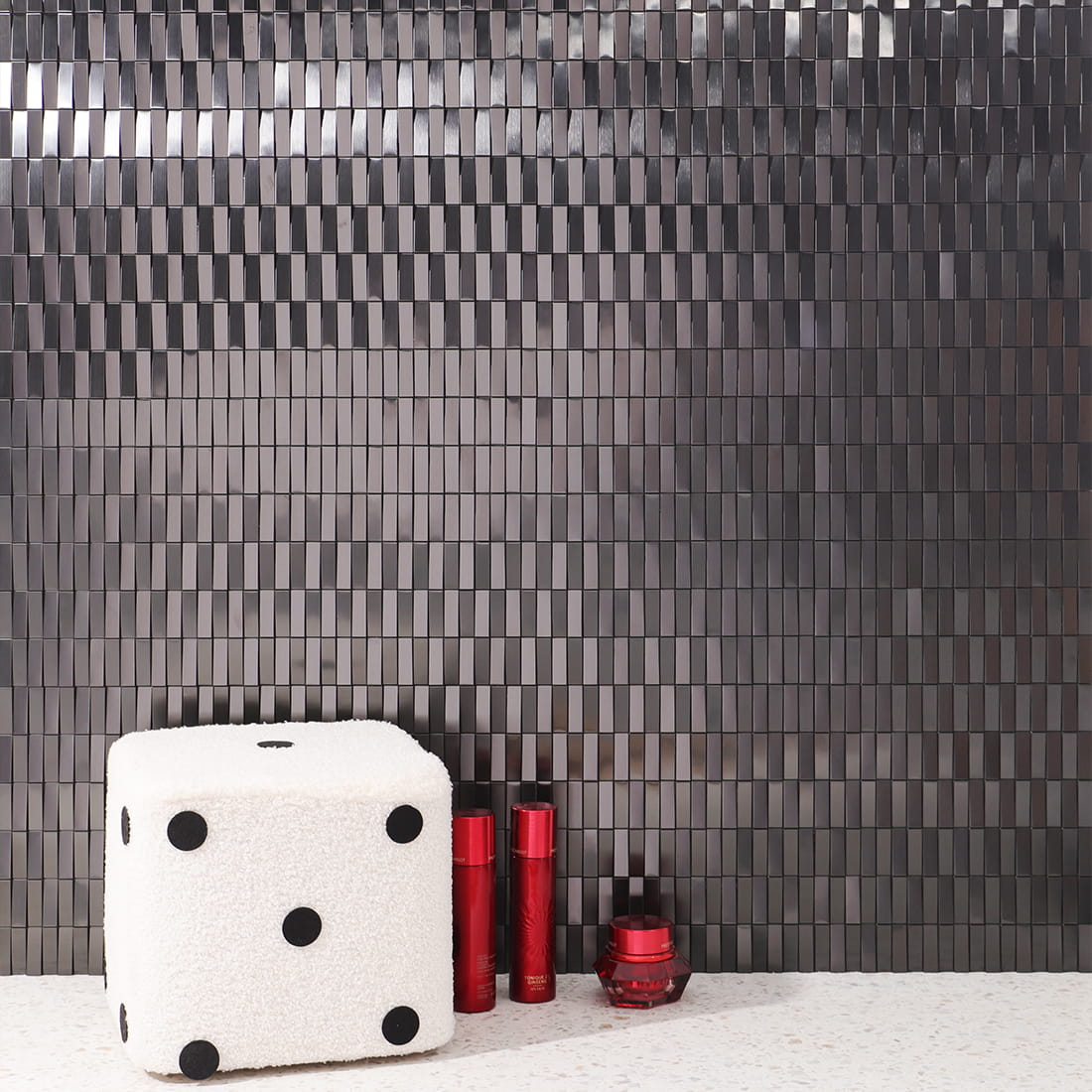 Full wall installation of black stainless steel rectangular mosaic tiles in a room.