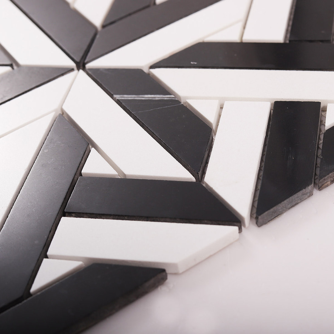 Angled close up showing thickness and smooth edges of black and white mosaic tile