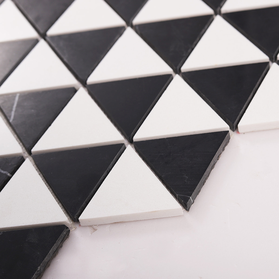 Angled close up showing thickness and edges of triangle marble mosaic tiles