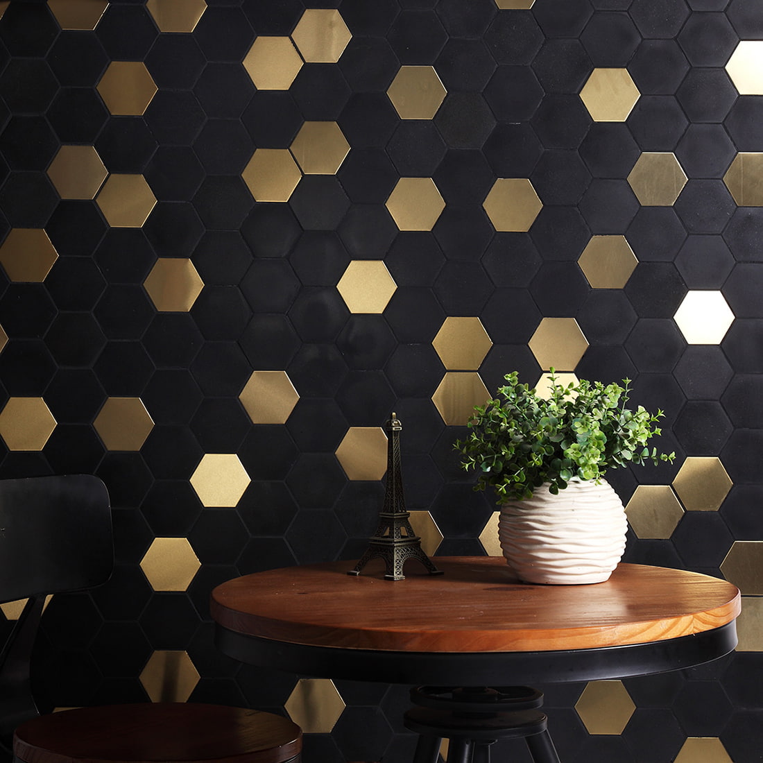 Decorative wall featuring black and gold hexagonal mosaic tiles behind a table.