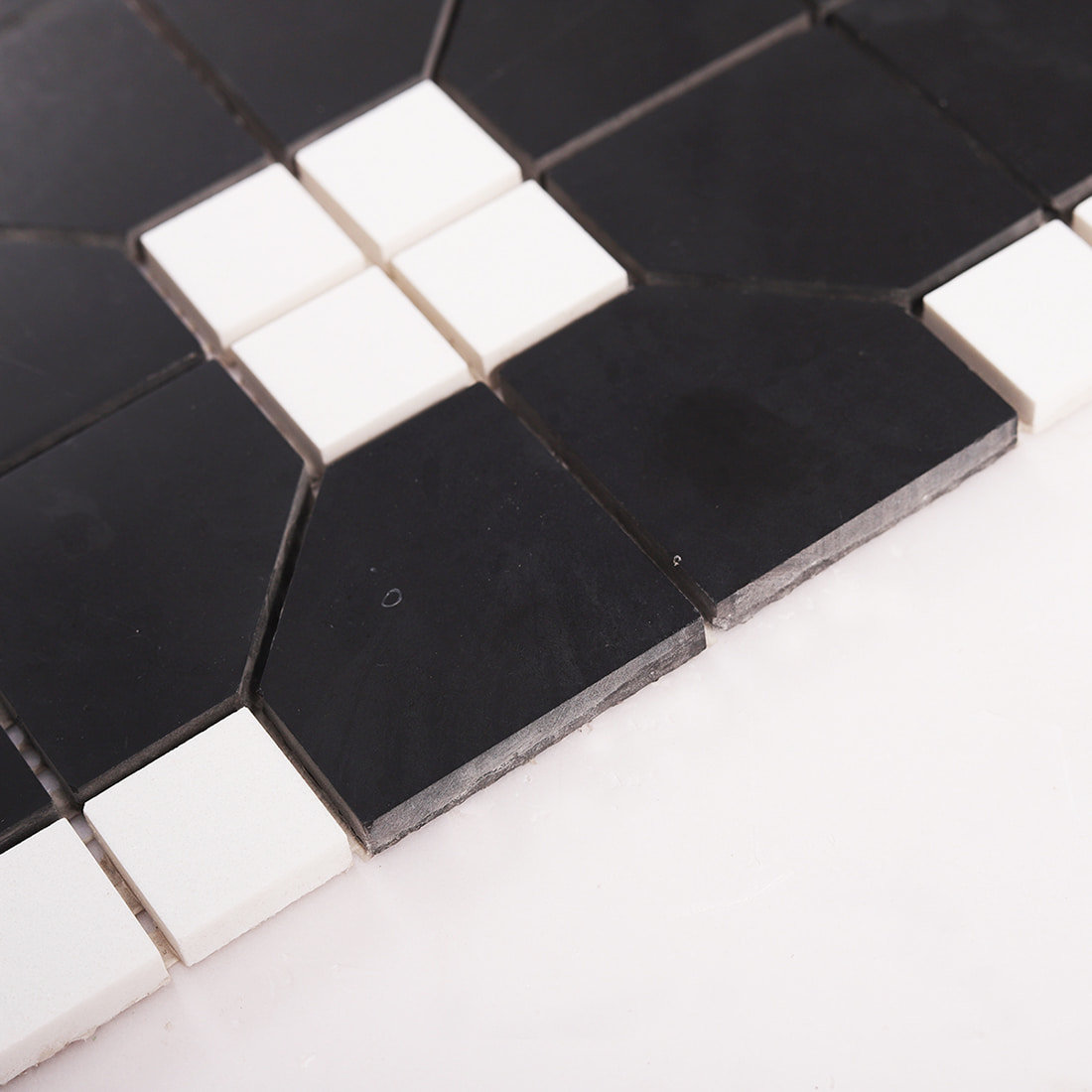 Side view of black marble mosaic tile showing thickness and stone layers