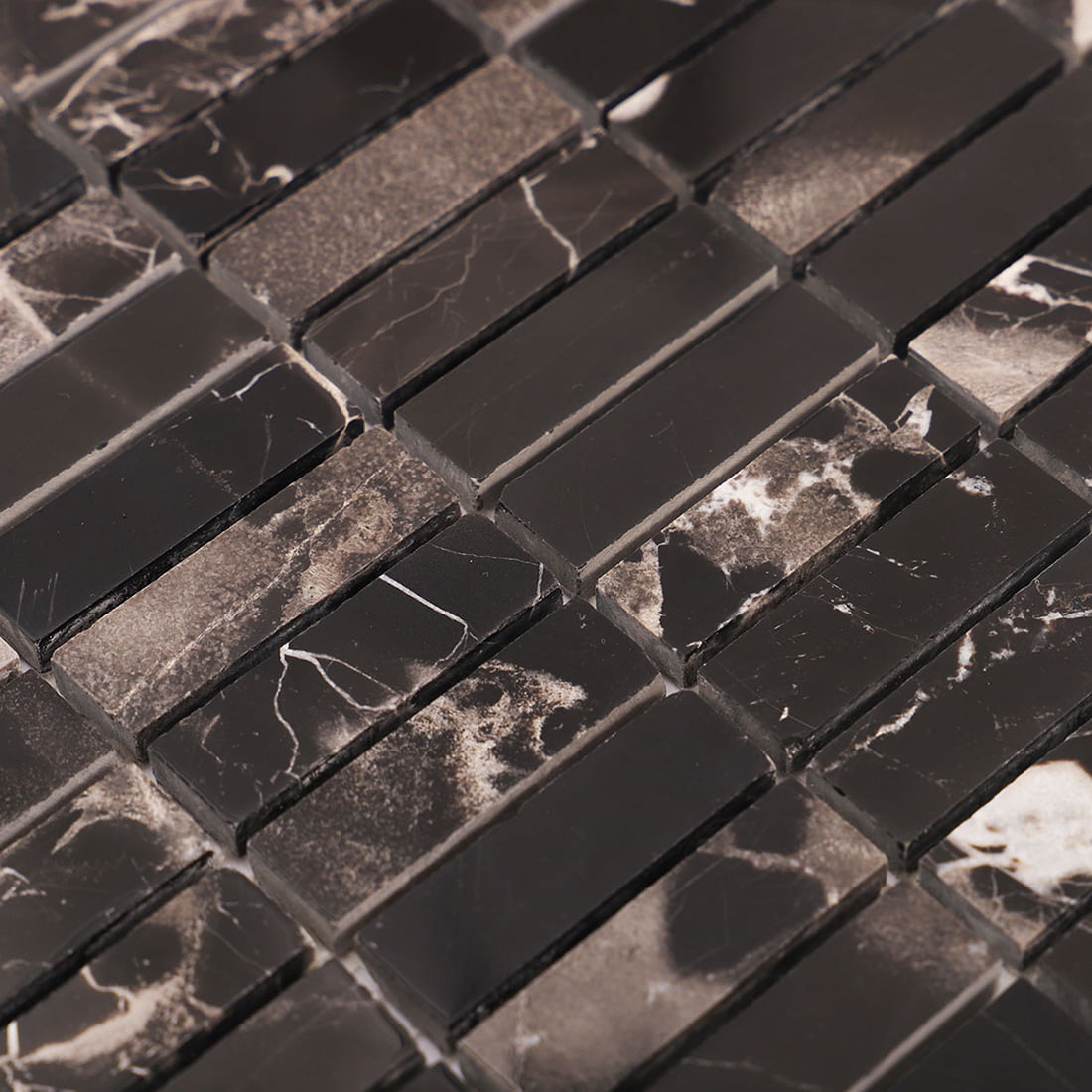 Angled close-up of black marble strip mosaic highlighting mixed stone pieces