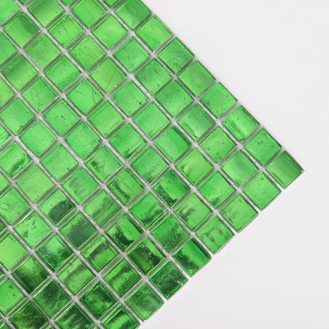 Diagonal corner close-up of bright green glass mosaic tiles with reflective foil finish