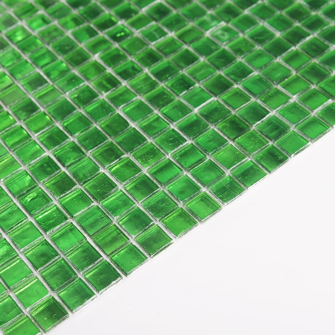 Edge view of bright green glass mosaic tiles showing thickness and reflective foil backing
