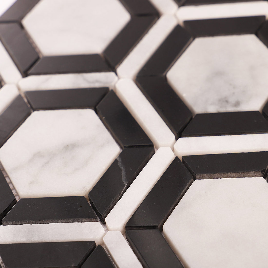 Angled close up of Carrara White and Nero Marquina hexagon marble mosaic surface
