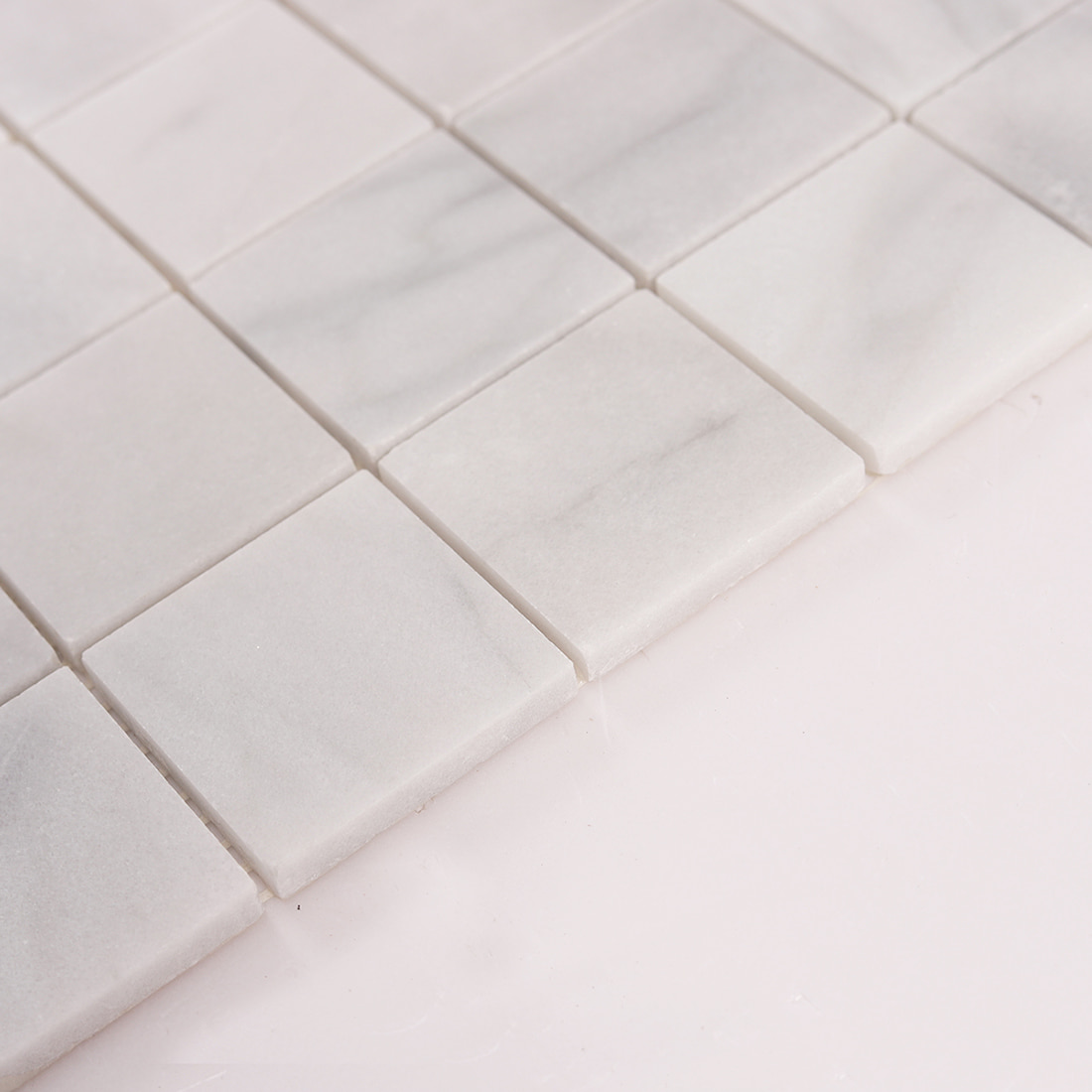 Angled view showing thickness of Carrara white large square marble mosaic tiles