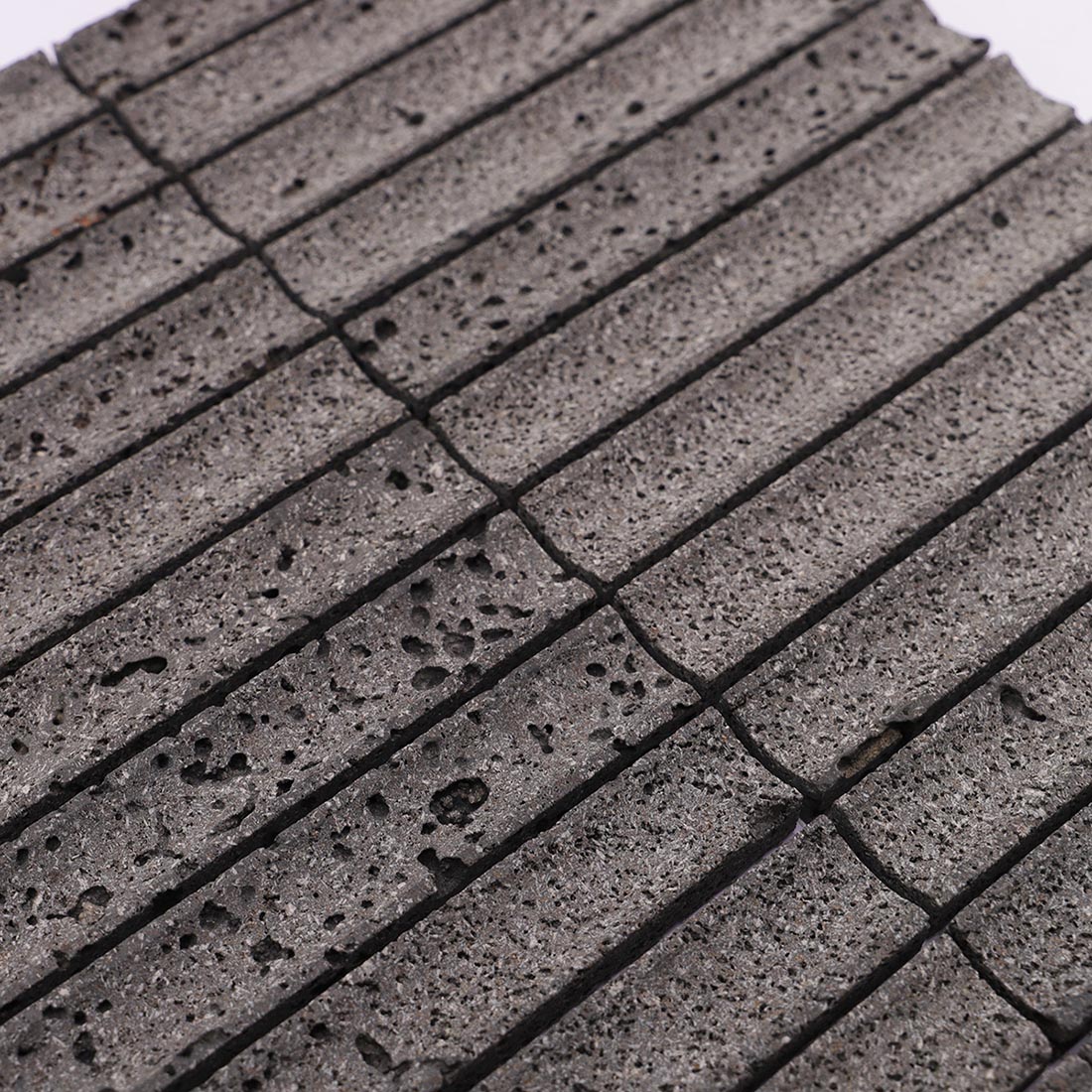 Close-up of charcoal gray grooved lava stone mosaic tiles with natural pores