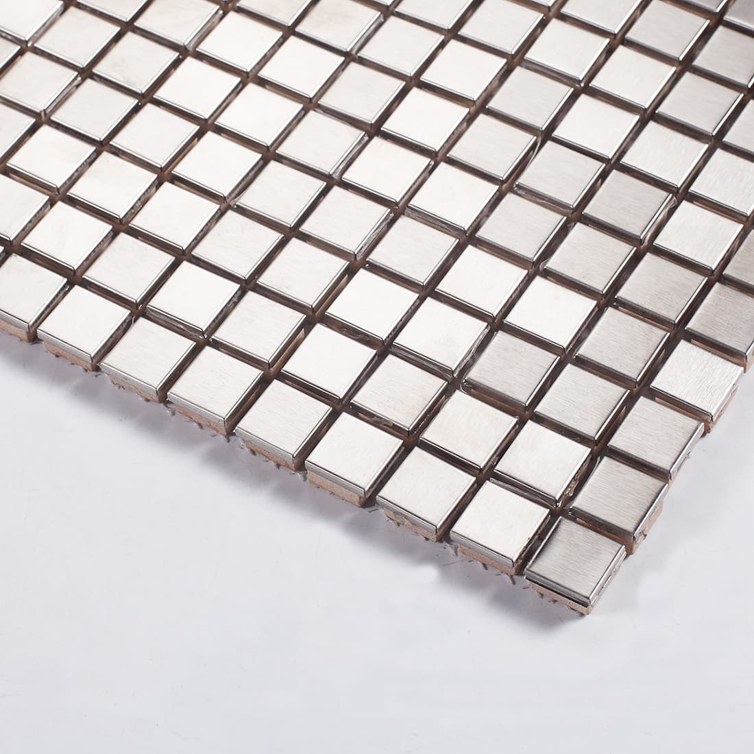 Angled close-up shot of silver metal square mosaic tiles highlighting the brushed texture.
