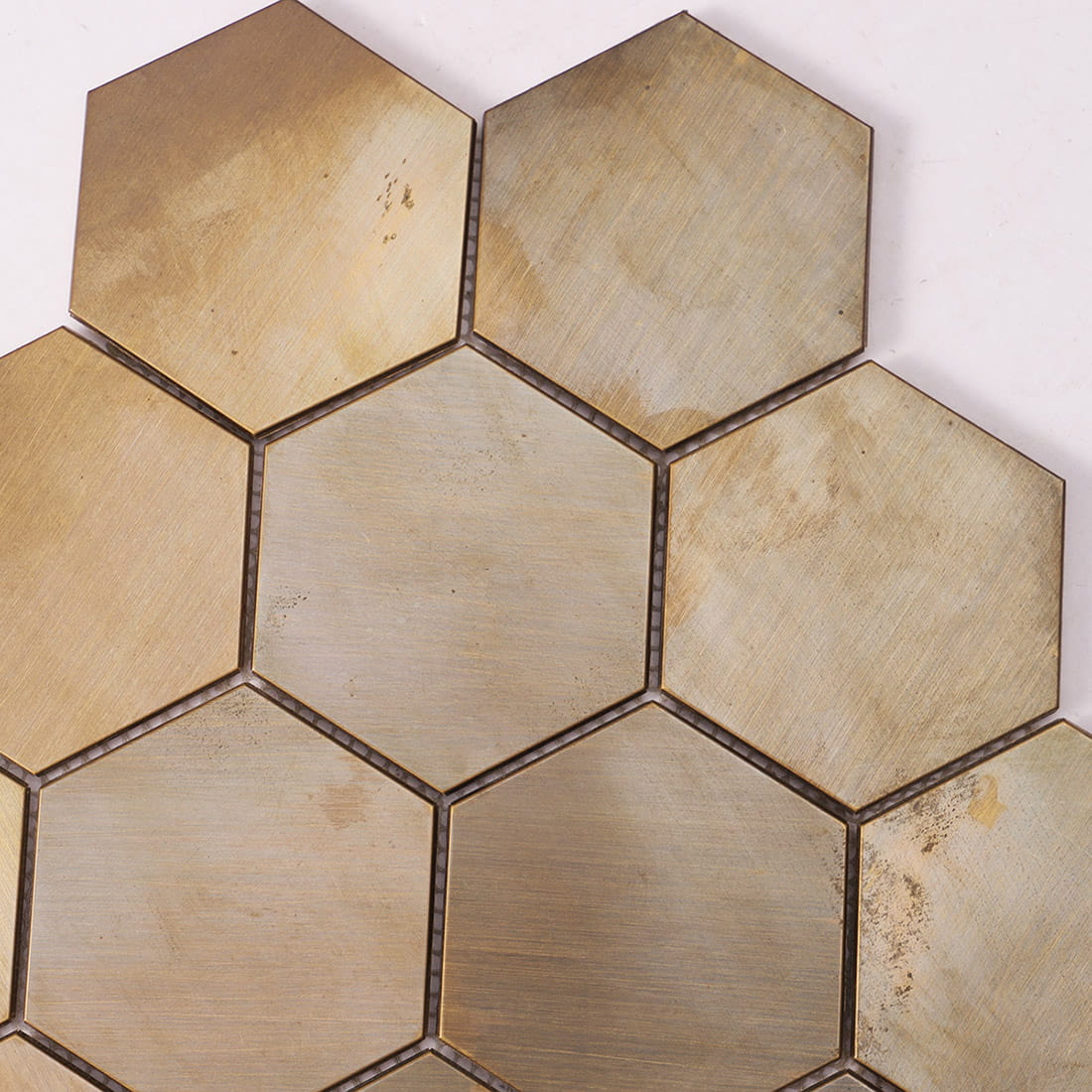 Close-up showing the weathered texture of antique brass hexagon metal tiles.