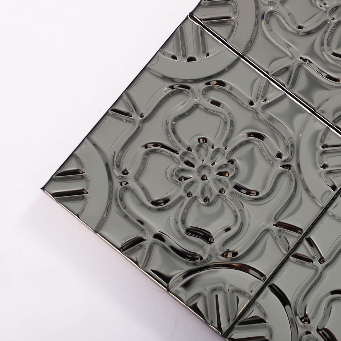 Close-up view of single black stainless steel floral embossed tile, showing texture