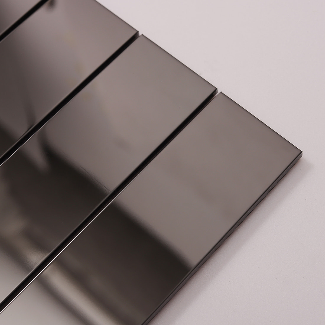 Close-up angled view of black mirror finish strip tiles showing reflections.