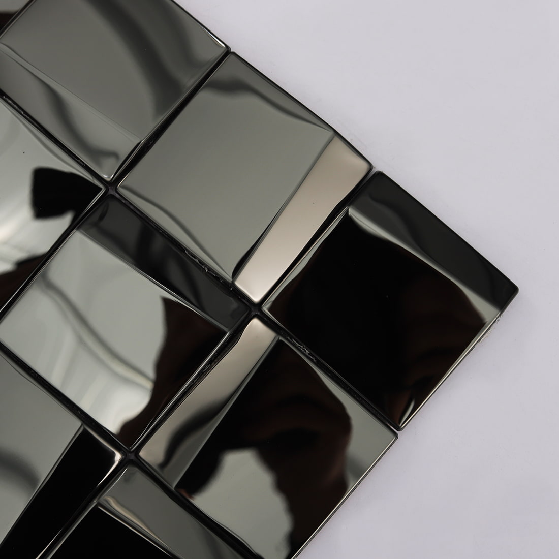 Close-up of black reflective 3D square mosaic tiles showing geometric facets.