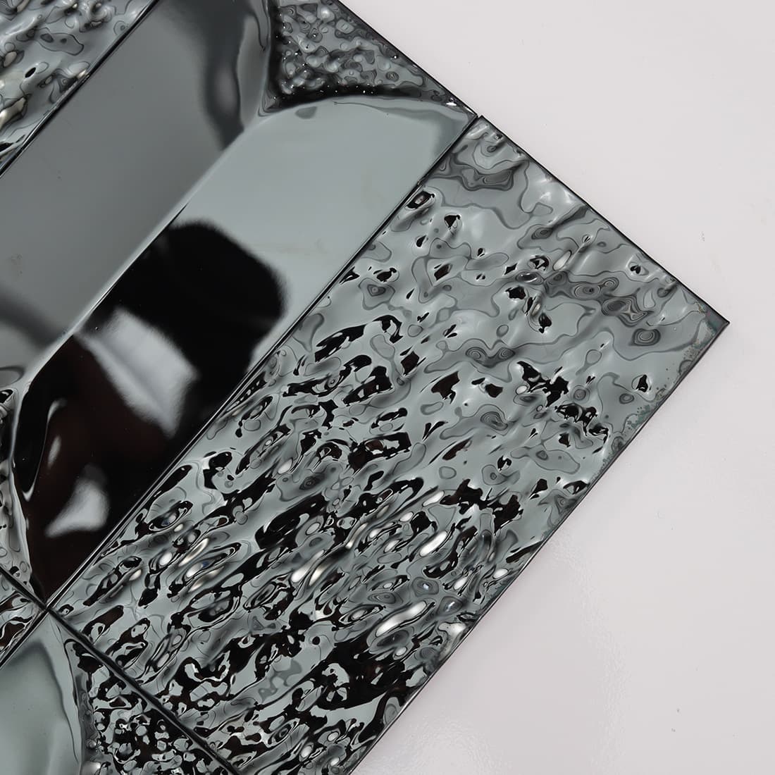 Close up of black stainless steel tiles with a water ripple effect.