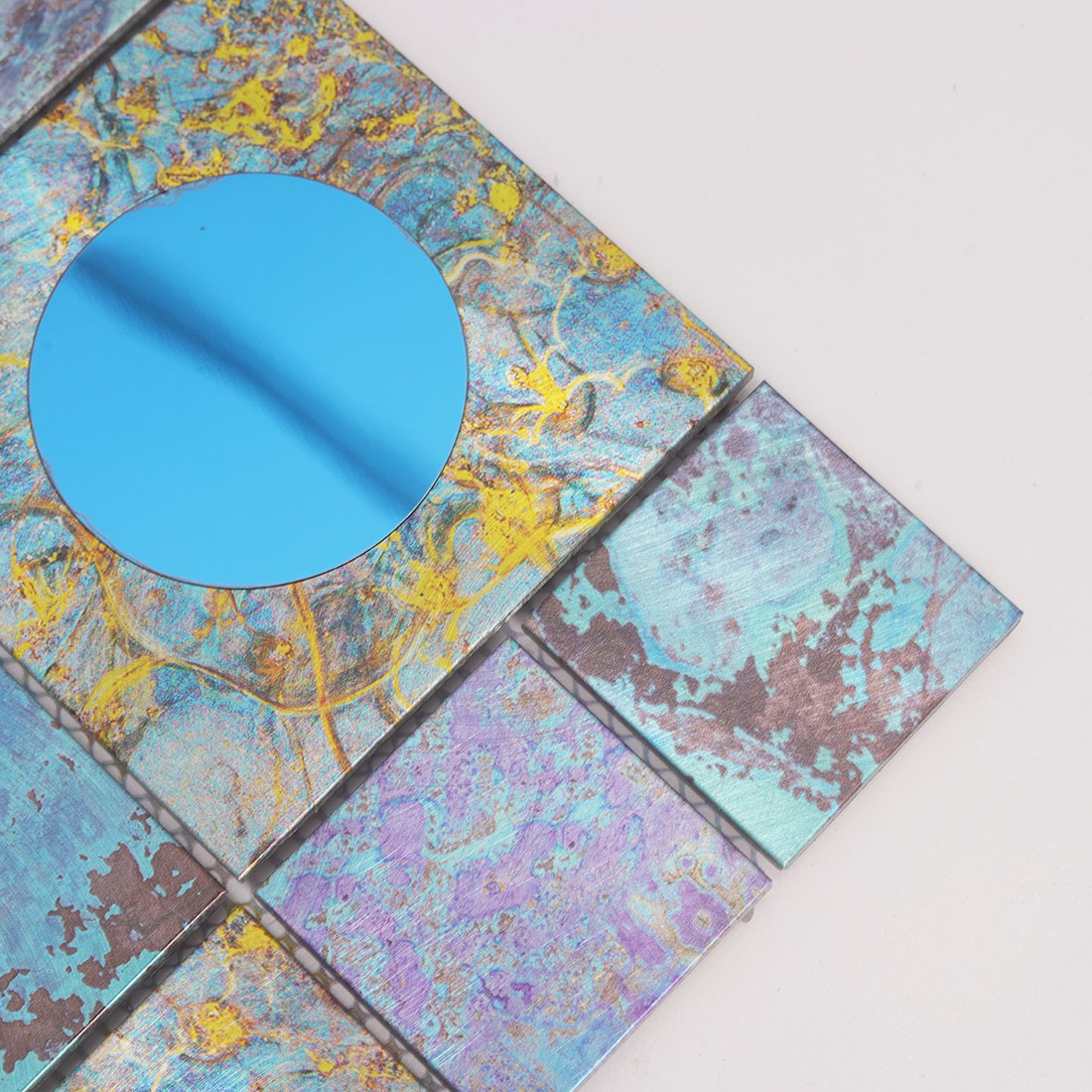 Close-up of blue round mirror glass on textured aluminum mosaic tile