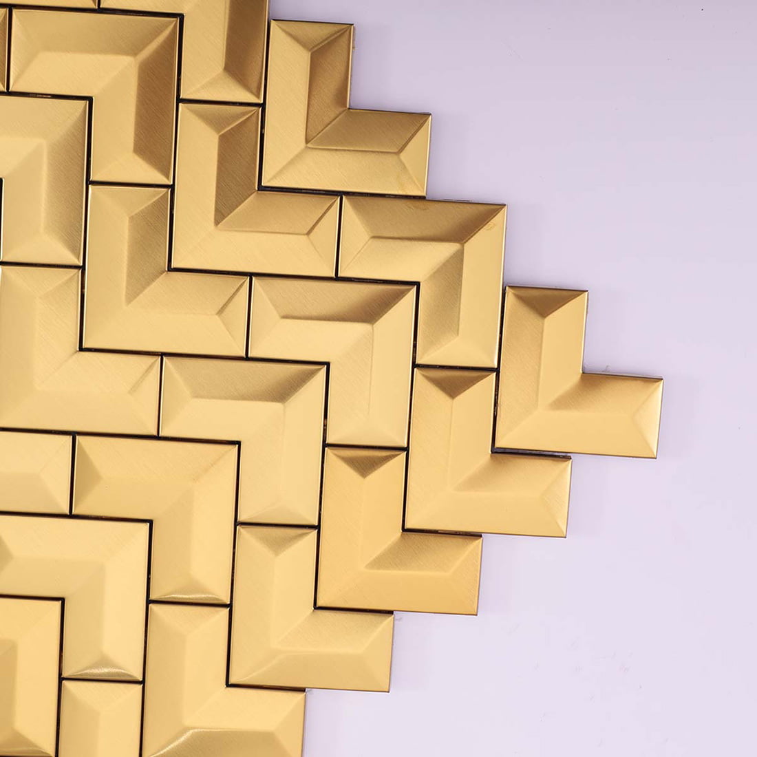 Close-up showing the beveled edges of brushed gold chevron metal tiles.