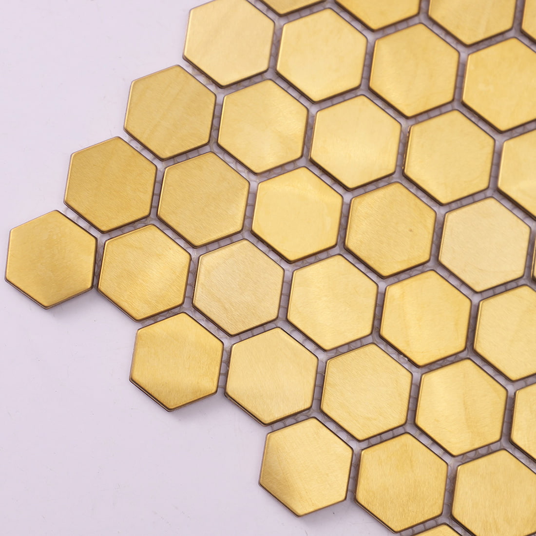Close-up view of brushed gold hexagon metal mosaic tiles on a white background.