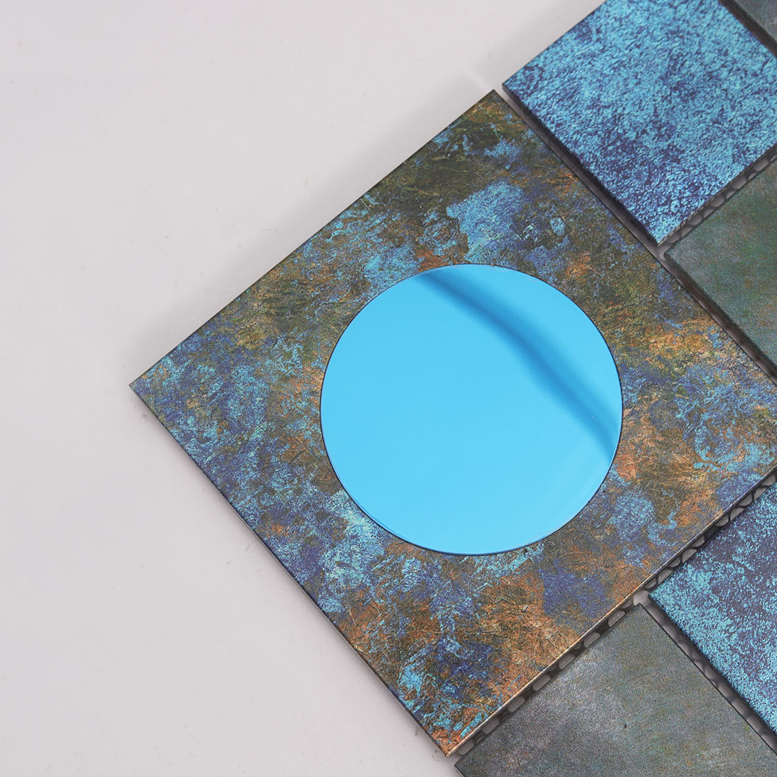 Close-up of blue round mirror glass on dark textured aluminum mosaic tile