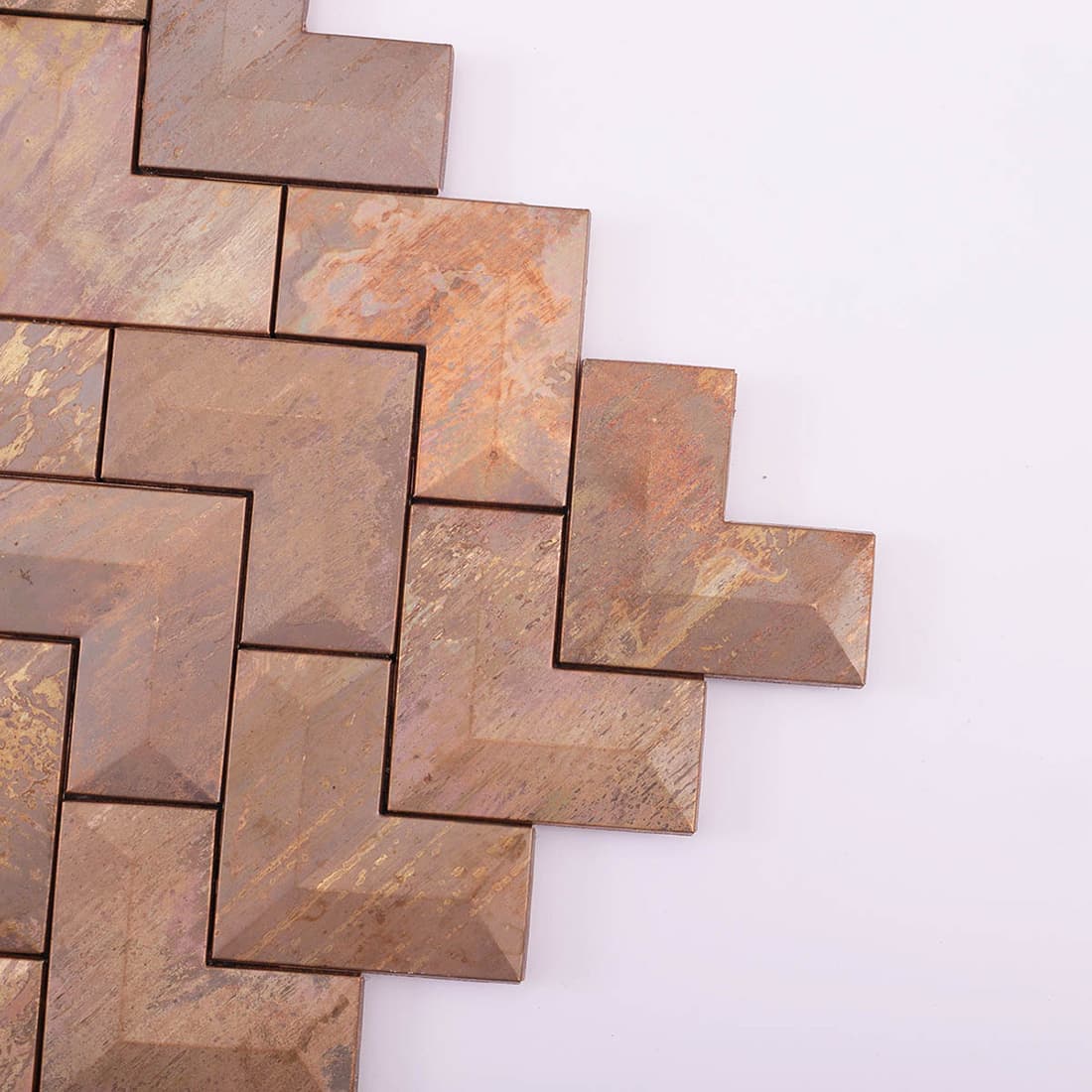 Close-up detail of the edges and corner of distressed copper chevron metal tiles.