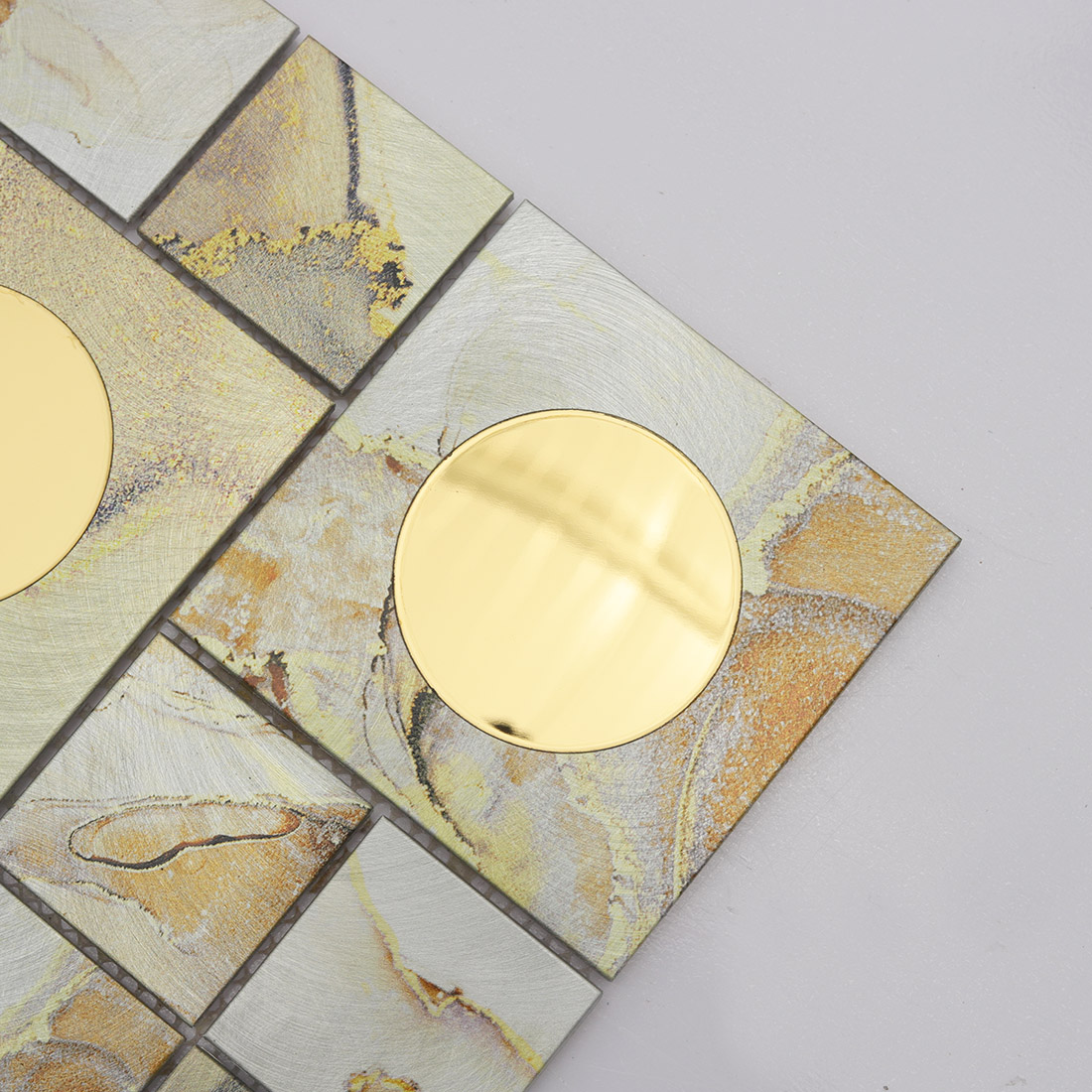 Close-up of gold round mirror glass set in cream aluminum mosaic tile