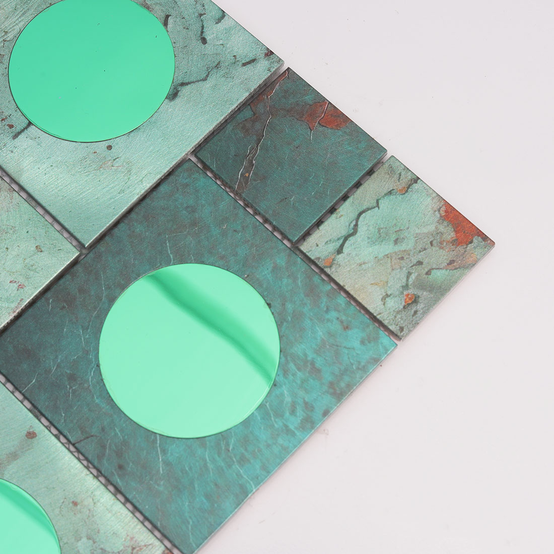 Close-up of green round mirror glass on textured aluminum mosaic tile