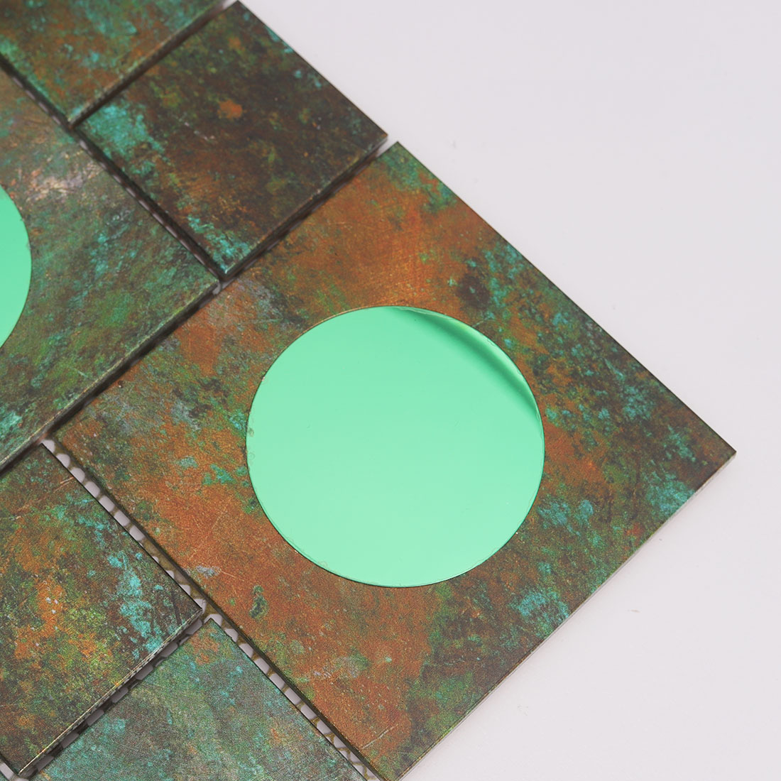Close-up of green round mirror glass on verdigris aluminum mosaic tile