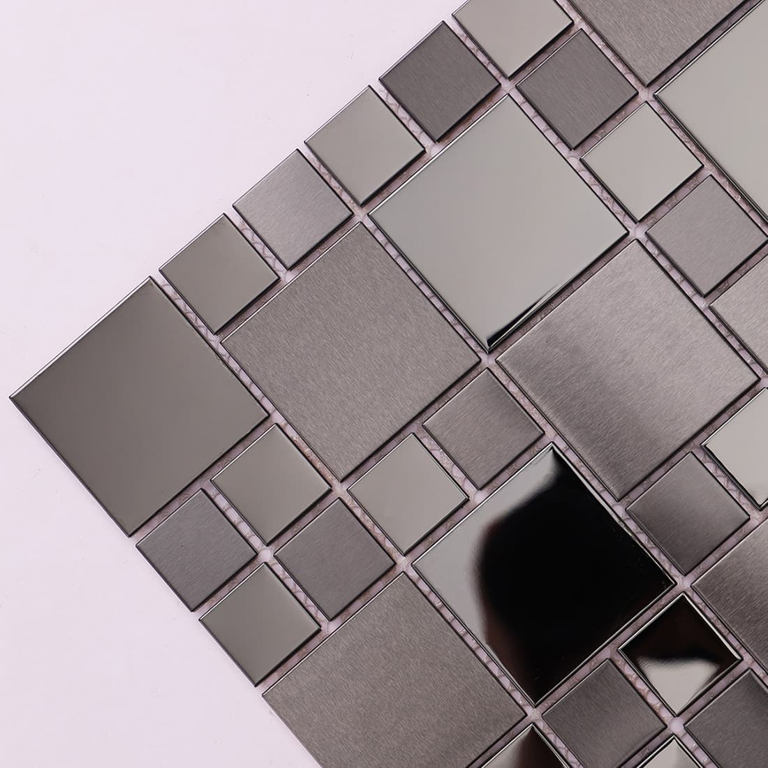 Close-up of gunmetal mosaic tiles featuring brushed and mirror-finish surfaces.