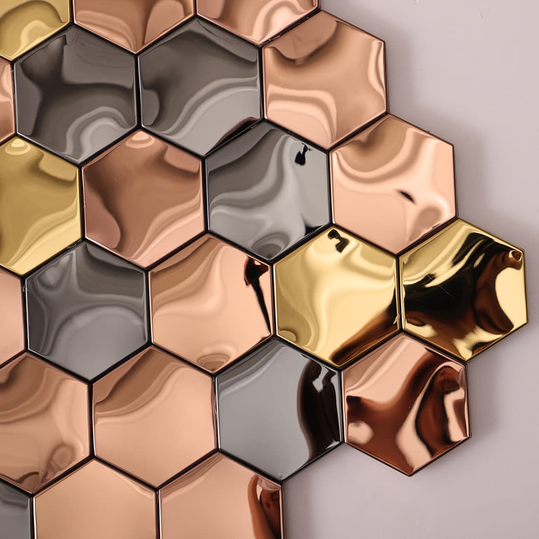 High-angle macro shot of reflective gold, silver, and copper hexagon tiles.