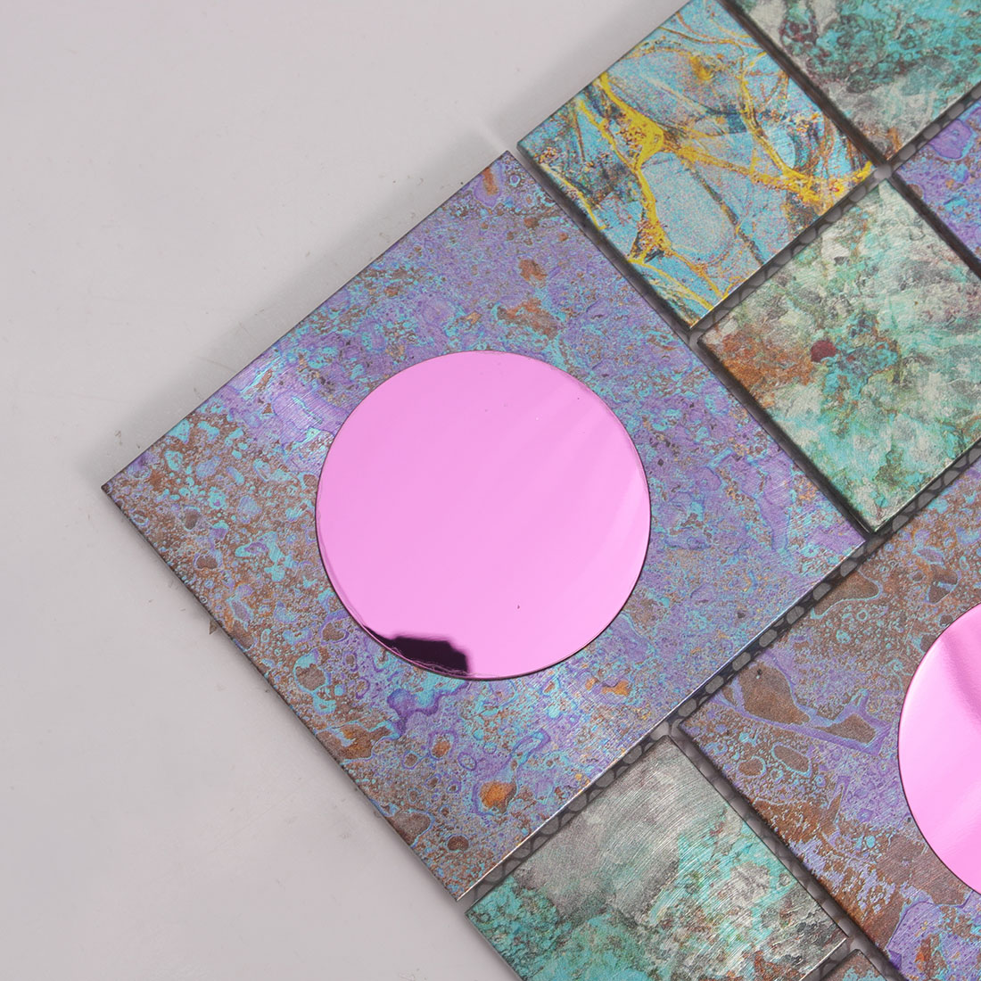 Close-up of pink mirror round glass on iridescent aluminum mosaic tile
