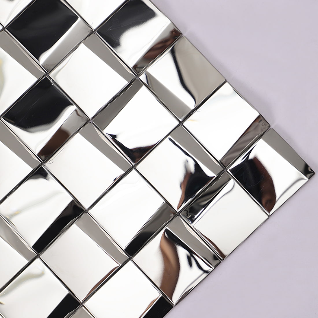Close-up of reflective silver 3D square mosaic tiles highlighting geometric facets.