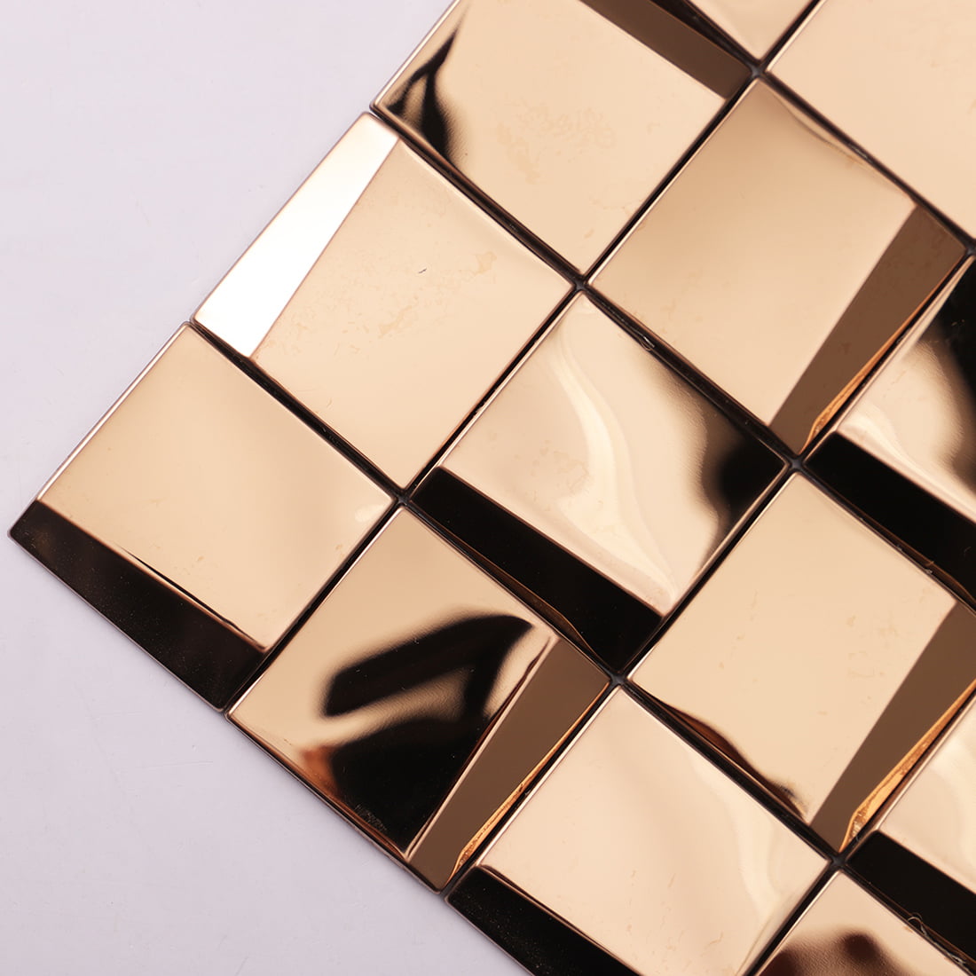 Close-up of rose gold reflective 3D square mosaic tiles showing metallic facets.