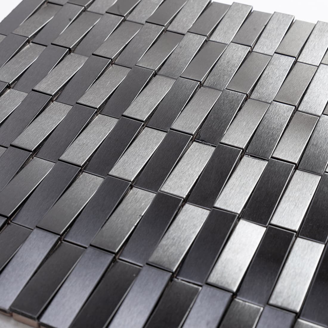 Close-up of black mosaic tiles showing mixed brushed and glossy rectangular chips.
