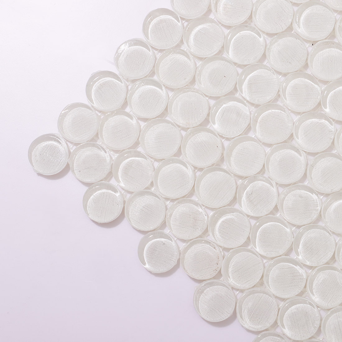 Close-up of white round glass tiles showing the mesh-backed edges.
