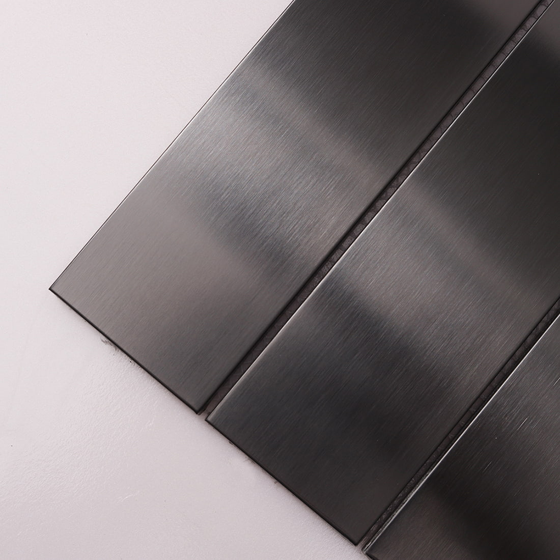Close-up showing the brushed texture of black stainless steel tiles.