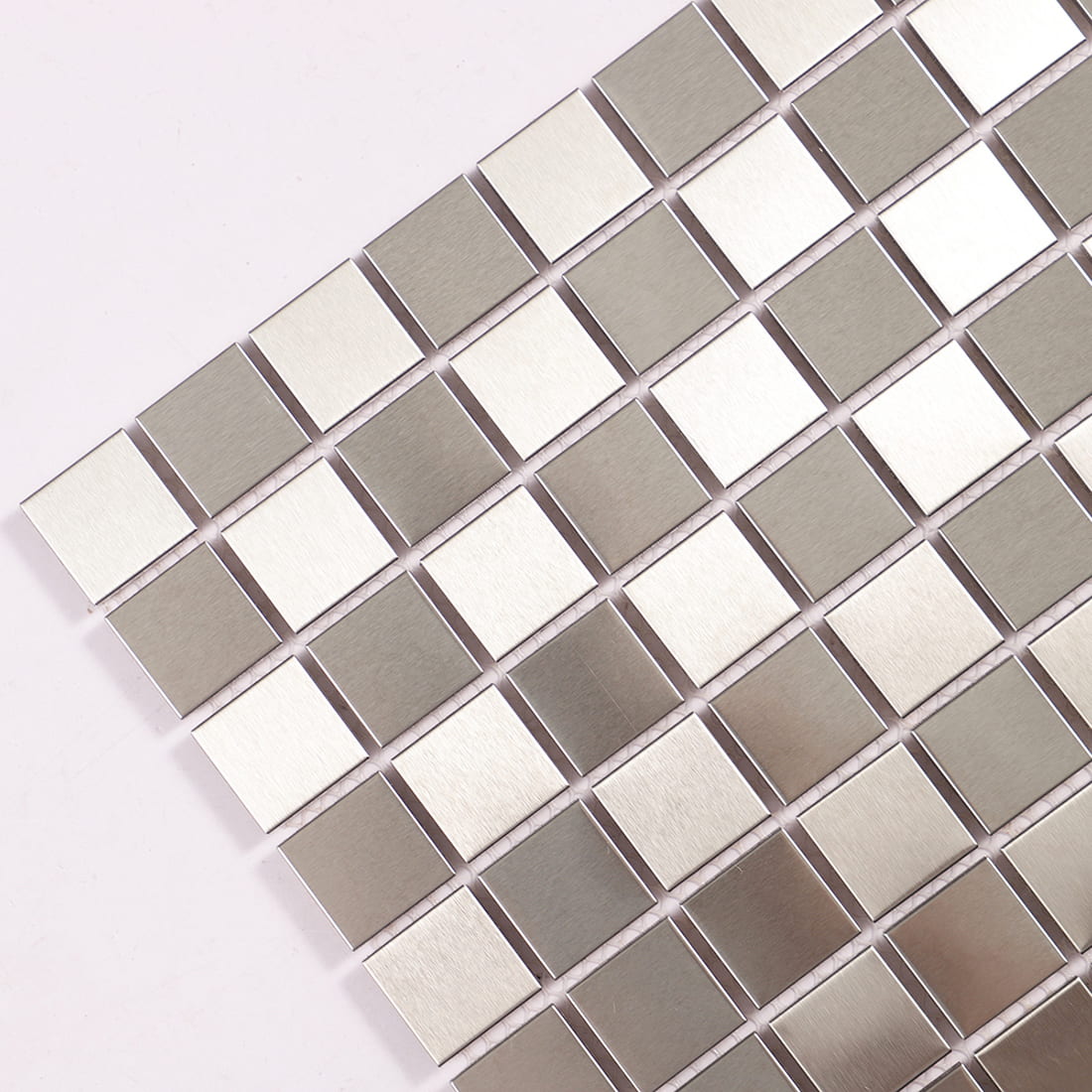 Close up of brushed and polished silver metal mosaic tiles at an angle.