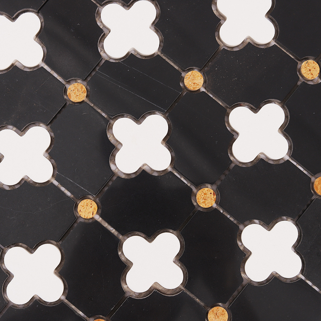 Close up of black tile field with white clover inserts and small gold round pieces