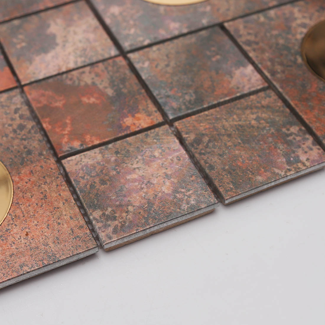 Edge detail of rustic copper aluminum mosaic tile with raised square chips